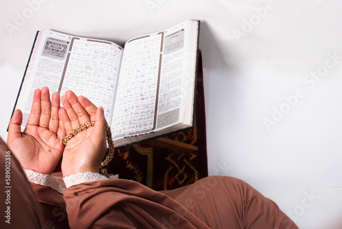 Islamic moslem woman reading Koran or Quran and praying with crystal tasbih