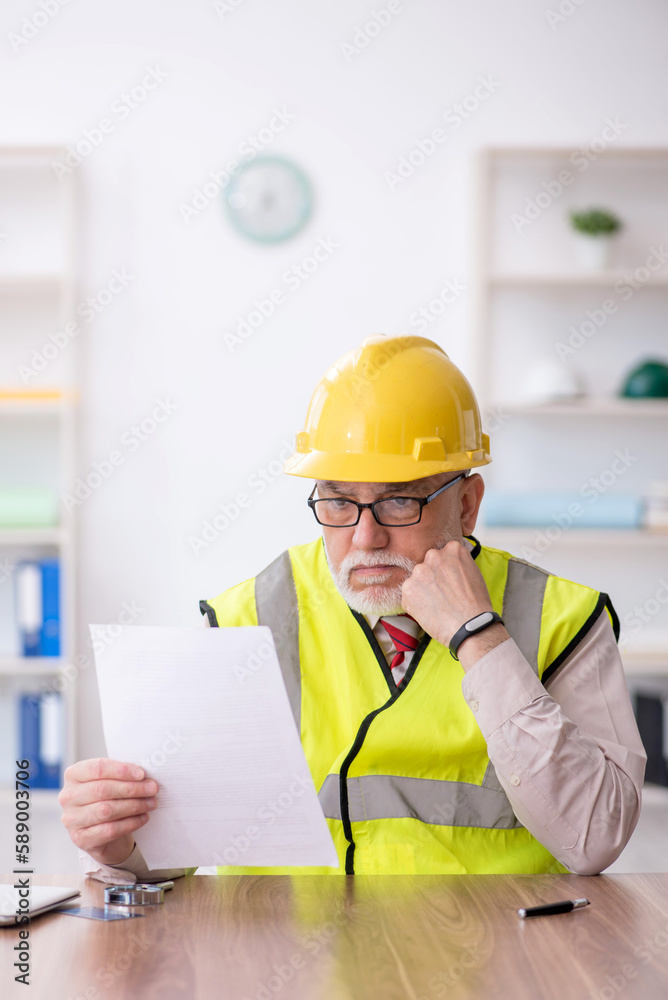 Old male architect sitting in the office Old male architect sitting in the office