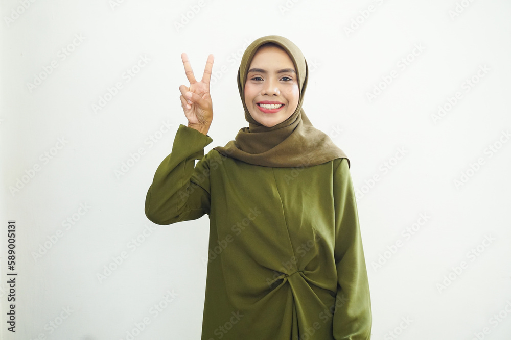 Cheerful young Asian woman in yellow dress showing peace sign over white background. Cheerful young Asian woman in yellow dress showing peace sign over white background.