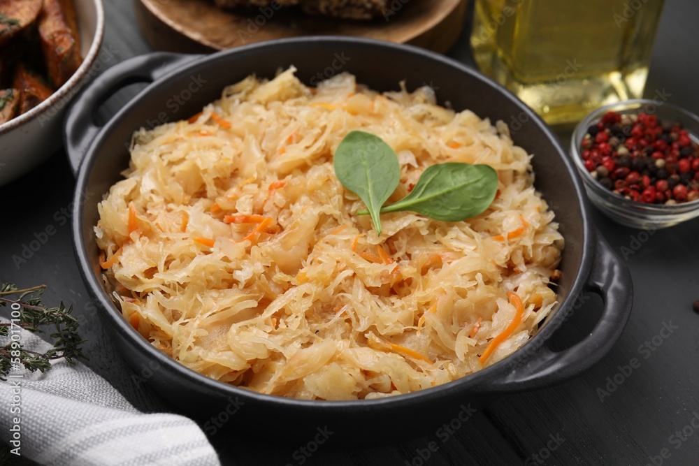 Serving pan with sauerkraut and products on black wooden table Serving pan with sauerkraut and products on black wooden table