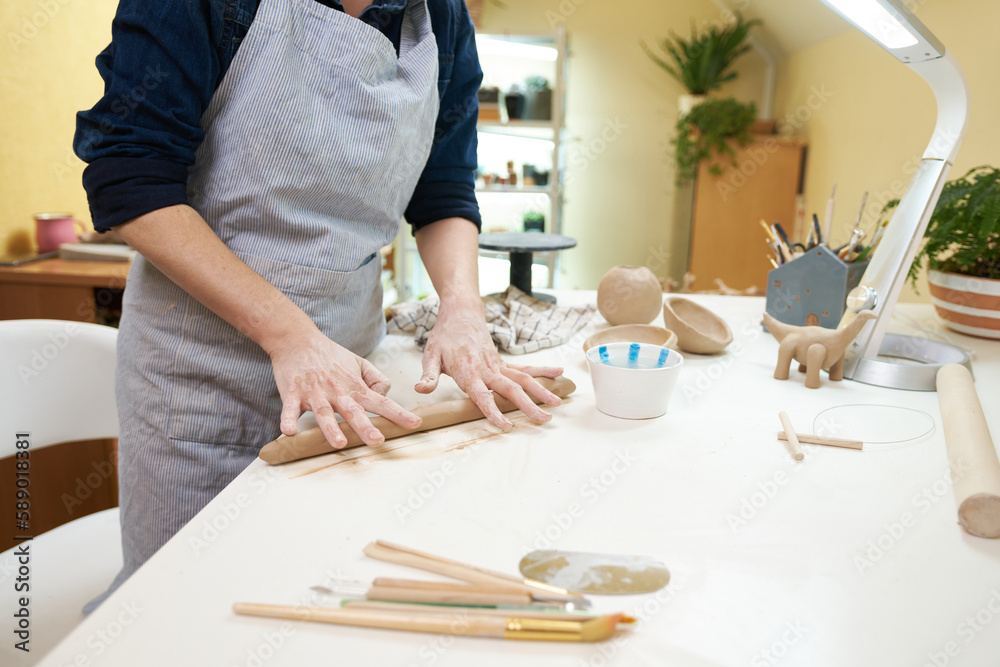 Hand-kneading technique in pottery - Woman wedging clay with hands standing behind table in studio Hand-kneading technique in pottery - Woman wedging clay with hands standing behind table in studio