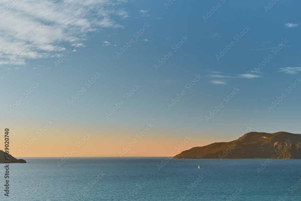 Magnificent sunset on the Aegean Sea with islands and a sailboat. Seascape, travel and yachting, idea for background or advertising of sea voyages