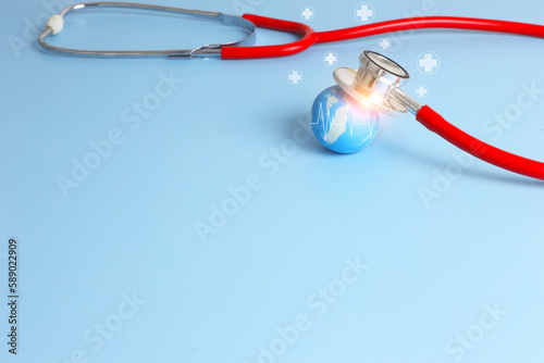 Checking health with red stethoscope on earth. World health day concept - blue earth with on light blue background.