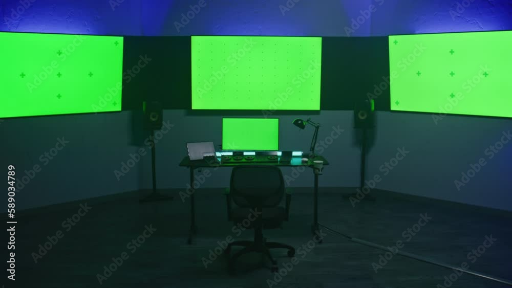 Studio with modern equipment for video color correction. Computer, digital tablet and big screens showing program interface, video footage. Color grading control panel. Post production. Green screen.