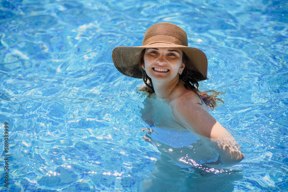 woman with a hat in the swimming pool.