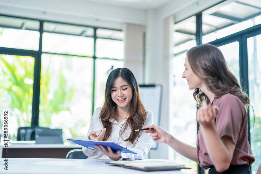 Smiling businesswoman working together on contract document, happy colleague meeting for planning new project in office Smiling businesswoman working together on contract document, happy colleague meeting for planning new project in office