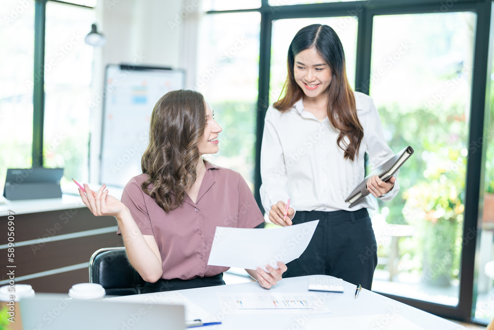 Smiling businesswoman working together on contract document, happy colleague meeting for planning new project in office Smiling businesswoman working together on contract document, happy colleague meeting for planning new project in office