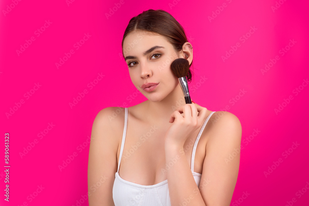 Girl hold blush blusher apply powder visage isolated over studio background. Woman powdering cheeks. Makeup brush. Female model gets blush powder on the cheekbones. Girl hold blush blusher apply powder visage isolated over studio background. Woman powdering cheeks. Makeup brush. Female model gets blush powder on the cheekbones.
