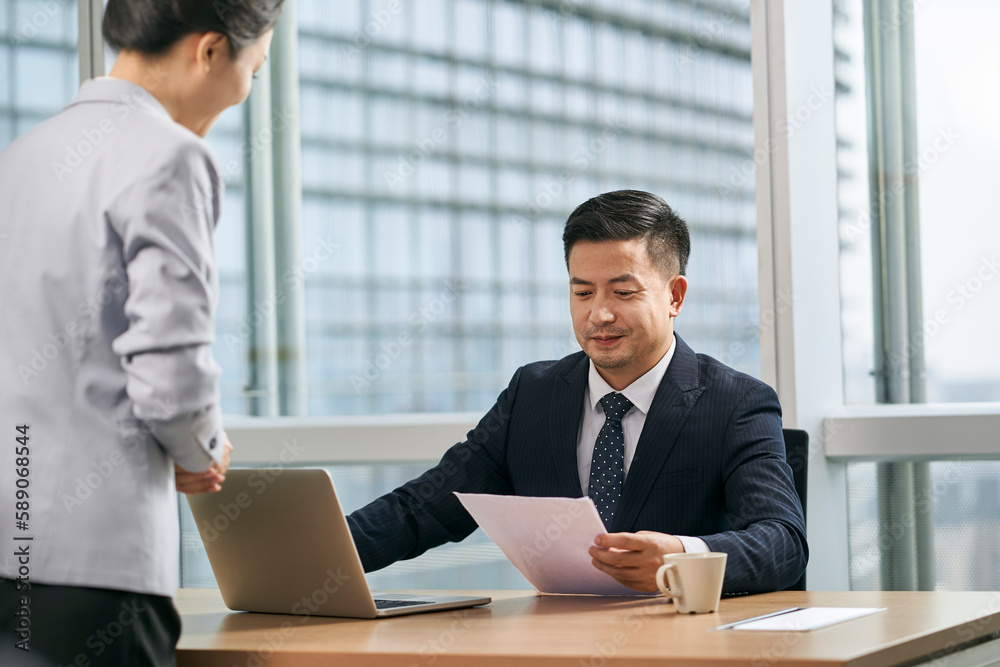 asian business manager reviewing a document in office asian business manager reviewing a document in office