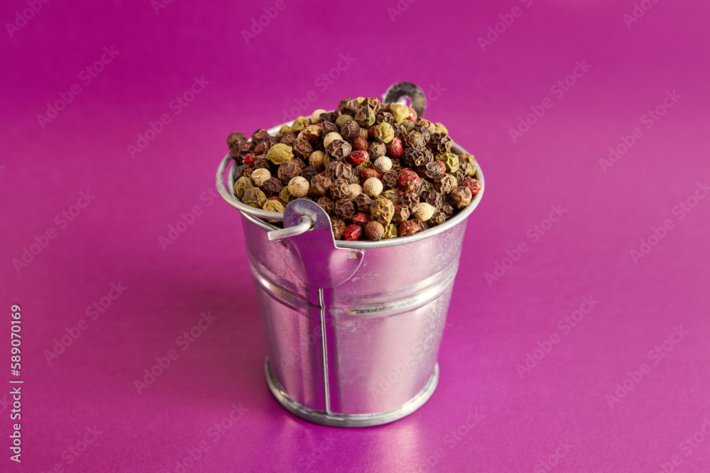The bucket is completely filled with a mixture of peppers in the shape of a pea. Black, pink, green, white pepper.