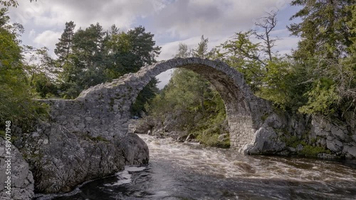 Medieval ancient Stone Packhorse Bridge over the Dulnain river, Carrbridge, Scotland, UK with strong water flow at sunset photo