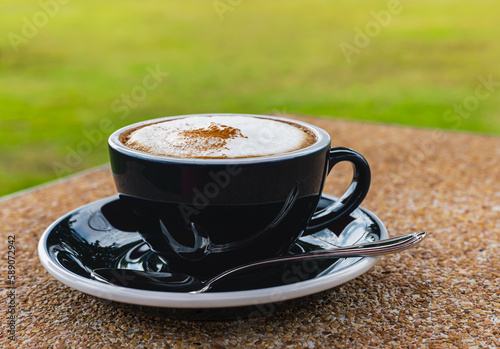 Obraz na płótnie Cup of cappuchino coffee sering in black ceramic cup at outdoor coffeeshop, Beve
