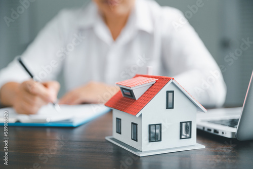 Real estate agents offer contracts to purchase or rent residential. Business person hands with home model, small building red house. Mortgage property insurance moving home and real estate concept.