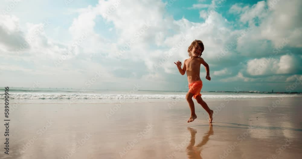 Boy run barefoot on the beach with smile and laugh, slow motion