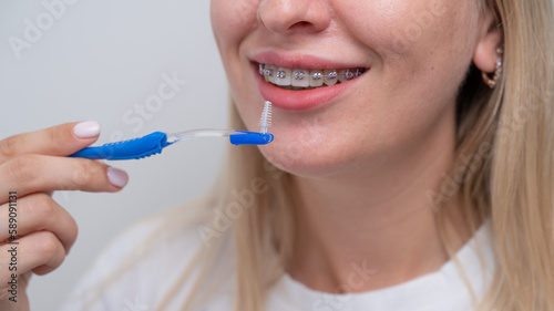 Caucasian woman cleaning her teeth with braces using a brush. Cropped portrait. 