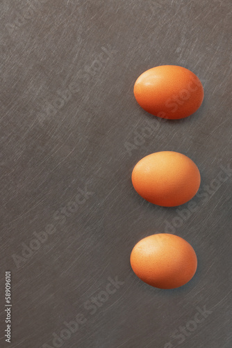 Three color eggs alined on vertical above aluminum surface