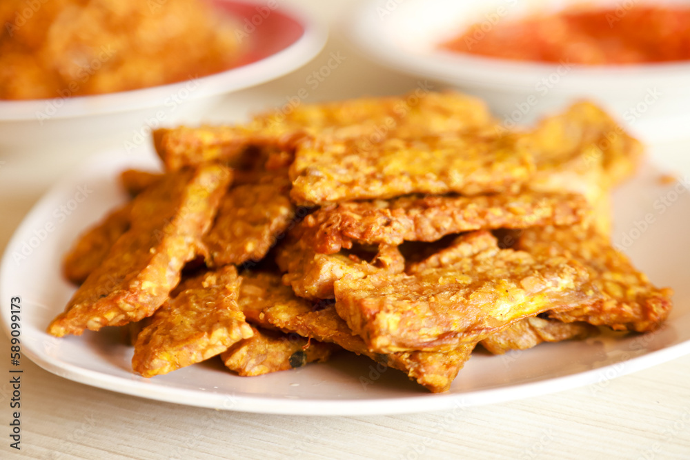 Tempe goreng or fried tempeh is served on a plate along with sambal Tempe goreng or fried tempeh is served on a plate along with sambal