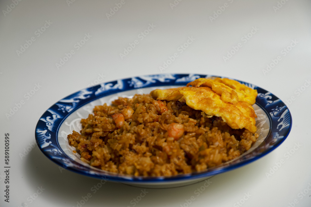 Nasi goreng kecap or soy sauce fried rice topped with scrambled eggs and prawns. Indonesian traditional food Nasi goreng kecap or soy sauce fried rice topped with scrambled eggs and prawns. Indonesian traditional food