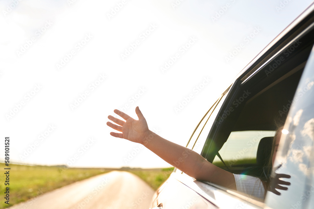 Unrecognizable child showing hand out of running car