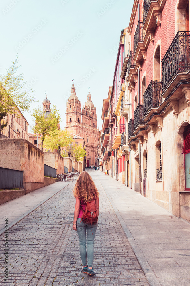 Woman walking in the street of Salamanca with cathedral view in the background- Spain