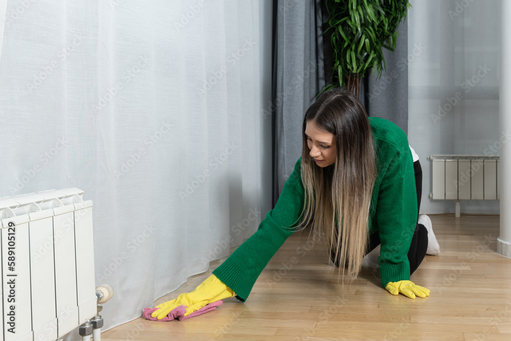 Young woman apartment owner for rent has rented out the apartment to students who left dirt and stains that she tries to clean and remove with a scrubbing sponge in order to rent out to new tenants Young woman apartment owner for rent has rented out the apartment to students who left dirt and stains that she tries to clean and remove with a scrubbing sponge in order to rent out to new tenants