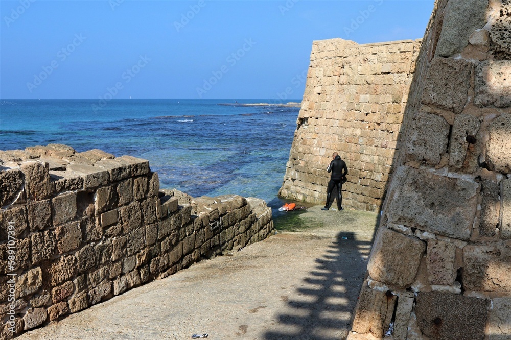 Professional diver standing between the old stone walls of the antique bastion near water