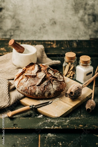 Vertical shot of a loaf of fresh bread on a wooden board in a rustic setting