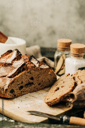 Vertical shot of a loaf and slices of fresh bread on a wooden board on a rustic background