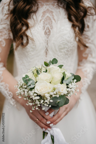 A bouquet of white roses in the hands of the bride