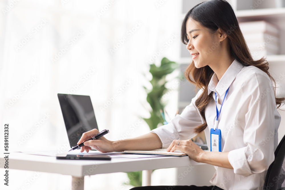 Charming Young asian businesswoman sitting on laptop computer in the office, asian employee business making report calculating balance Internal Revenue Service checking document. Charming Young asian businesswoman sitting on laptop computer in the office, asian employee business making report calculating balance Internal Revenue Service checking document.