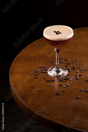 espresso martini cocktail in glass served under rubber holder with spilled coffee beans on bistro table corner top view