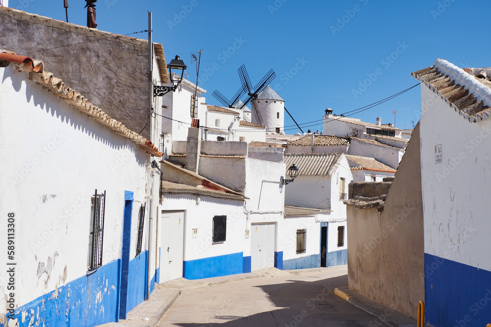 beautiful street in campo de criptana with windmills in the background