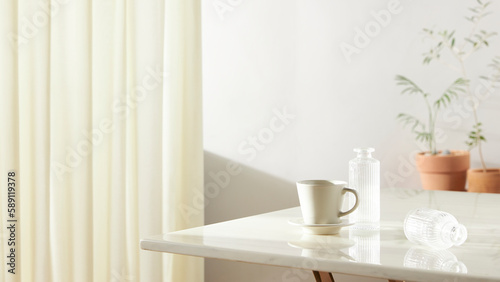 A room with a calm atmosphere, with clay pots placed in front of the wall and curtains letting in natural light. Glass bottles, coffee, and various objects on a marble table. © gru pictures
