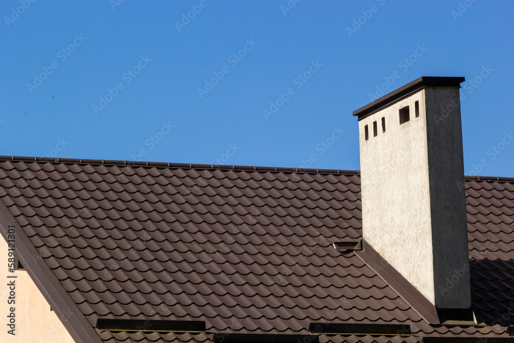 Roof of a new home. Ceramic chimney, metal roof tiles, gutters, roof window. Single family house