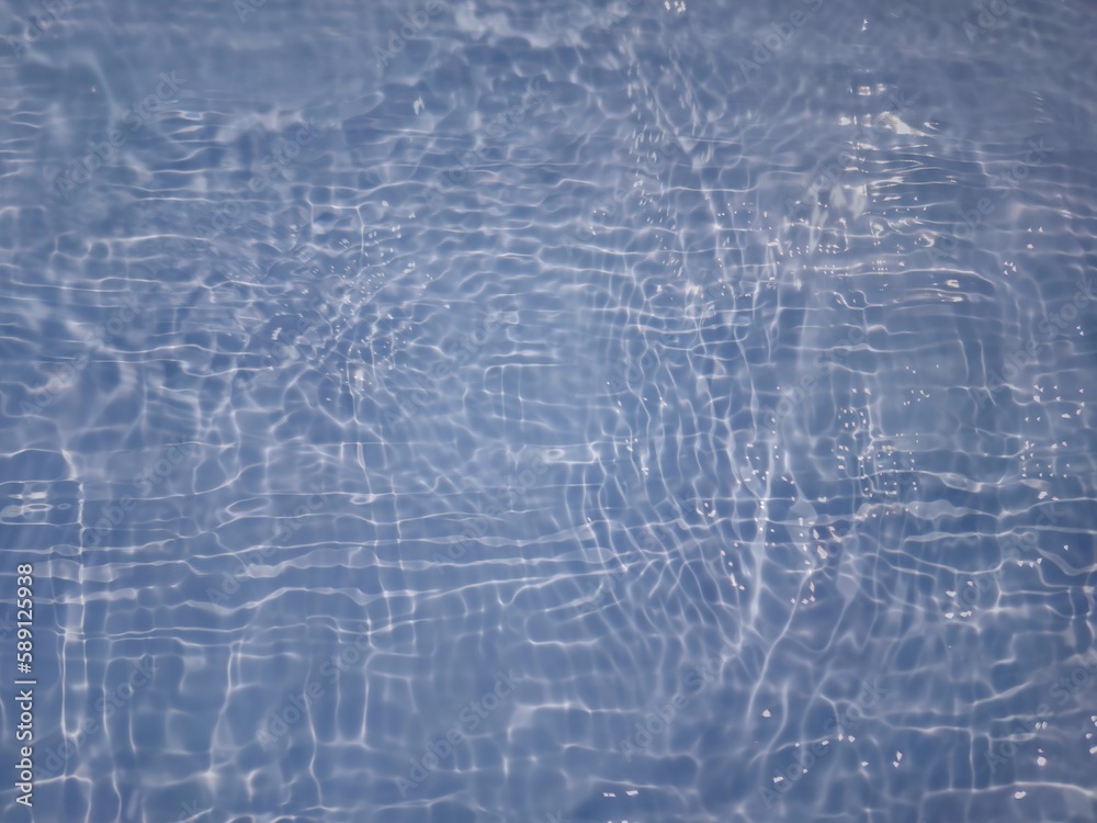 Defocus blurred transparent blue colored clear calm water surface texture with splashes and bubbles. Trendy abstract nature background. Water waves in sunlight with copy space. Blue water shine