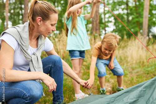 Mother setting up tent for camping during vacation