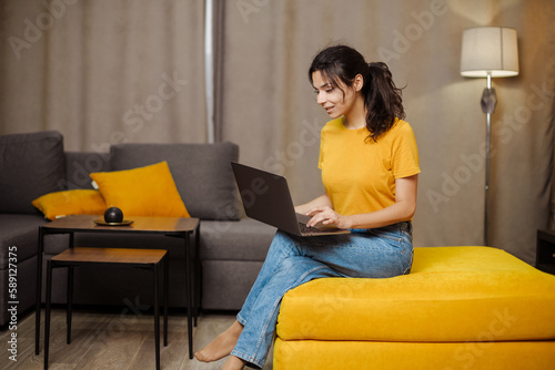 Happy indian or arabian young freelance woman on sofa and using laptop. Remote working