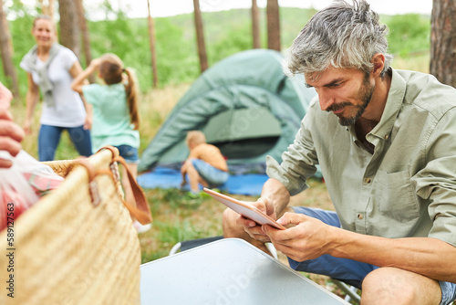 Man using digital tablet with family in background