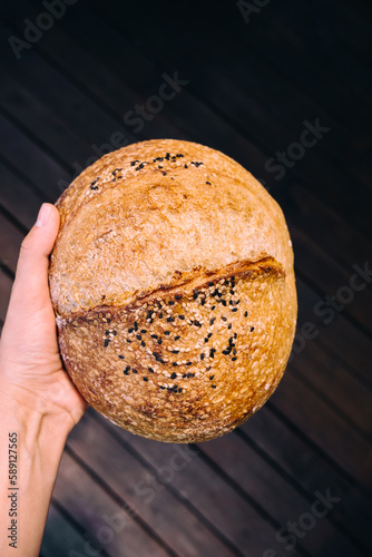 Female hand holding homemade sourdough bread. Freshly baked with seeds. 
