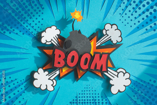 Handmade colorful paper cutting speech bubble with text boom. Pop art and comic style. Blue background. 