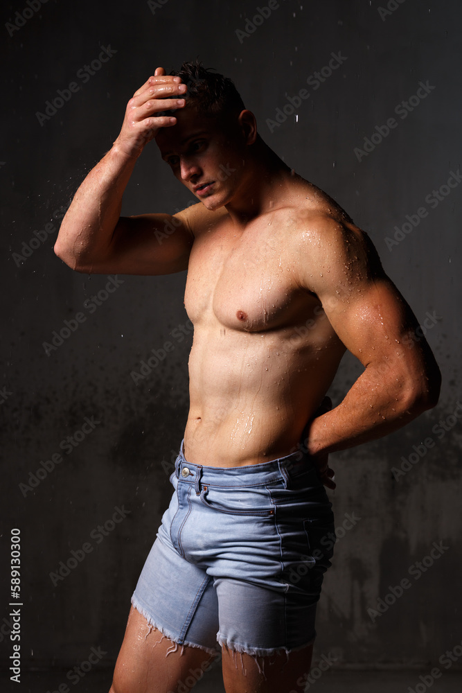 Fototapeta premium Athlete bodybuilder trains in the studio in the rain.