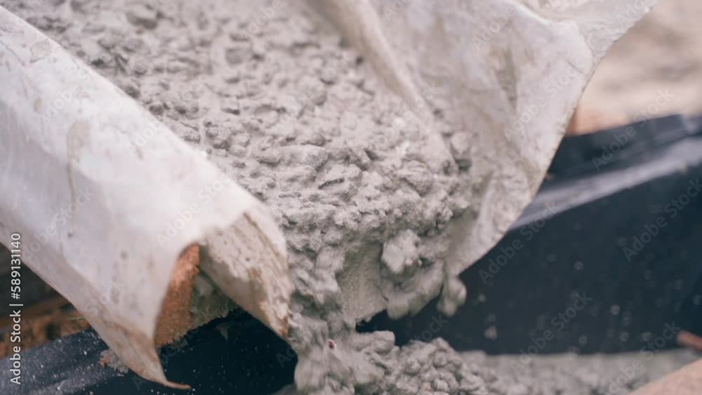 Thick concrete mortar flows into the formwork of the foundation, in