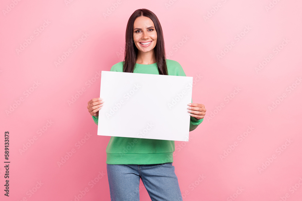 Portrait of satisfied adorable girl straight hairdo wear green pullover hold white placard empty space isolated on pink color background Portrait of satisfied adorable girl straight hairdo wear green pullover hold white placard empty space isolated on pink color background