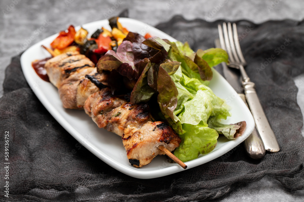 Grilled meat on stick with spices, vegetables and fresh salad