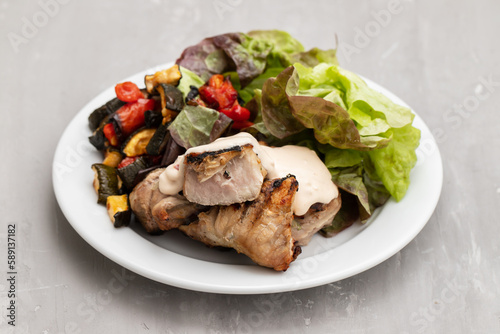Baked pork with vegetables and fresh salad on plate