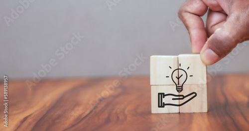New idea, solution, suggestion concept. Hand puts the wooden cubes with light bulb on hand icon on beuatiful grey background and copy space. Business review, strategy suggestion for business growth