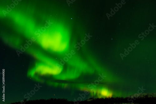 imagen de un paisaje nocturno nevado, con montañas de fondo, y una aurora boreal sobre el cielo de Islandia 