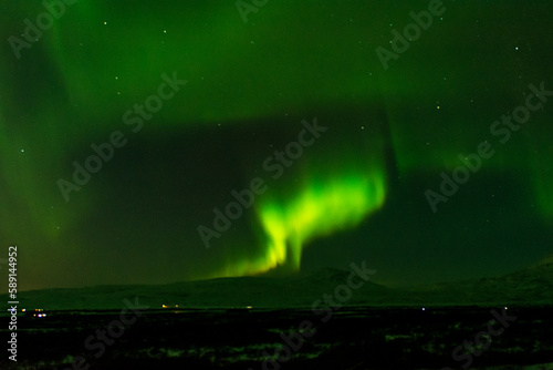 imagen de un paisaje nevado nocturno con montañas al fondo y una aurora boreal sobre el cielo de Islandia  © carles