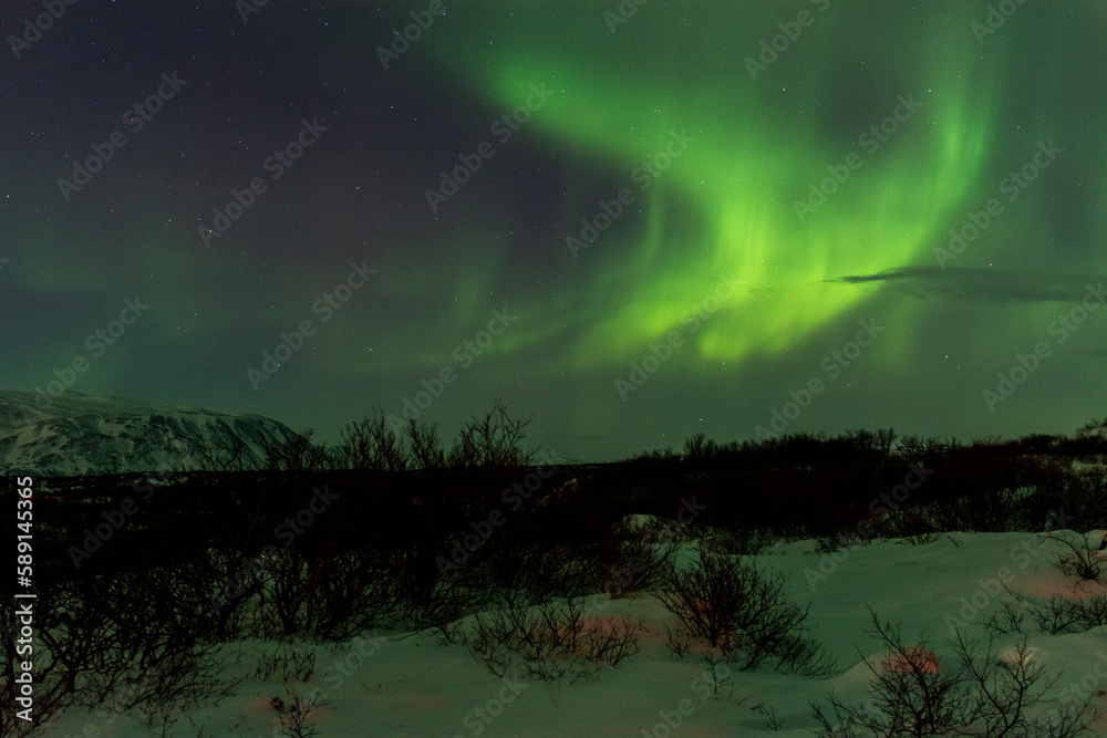 imagen paisaje nocturno con montañas al fondo y una aurora boreal en el cielo estrellado de Islandia 