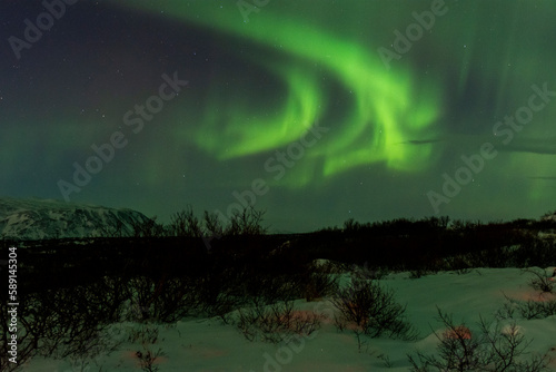 imagen nocturna de un paisaje nevado con una aurora boreal en el cielo nocturno de Islandia 